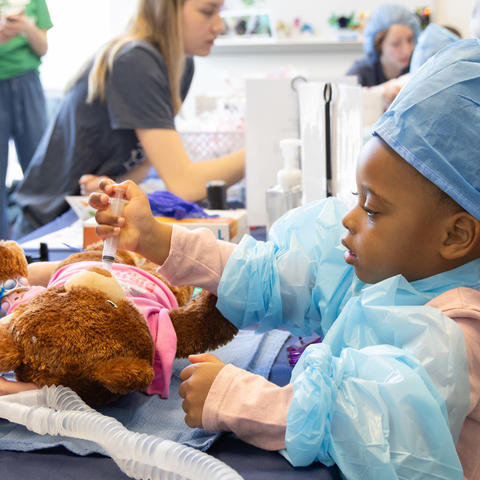 image of little girl in scrubs playing doctor with her bear