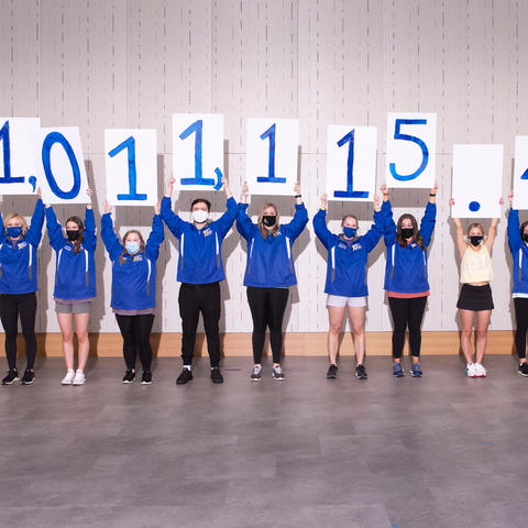 Photo of students holding up signs revealing the DanceBlue fundraising total of $1,011,115.49.