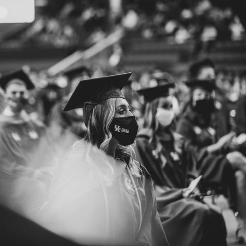 Image of graduates seated at Commencement wearing face masks and caps and gowns