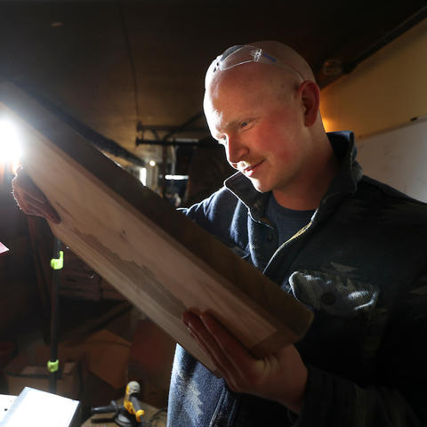 Image of Jacob Whitt inspecting a piece of wood in his workshop