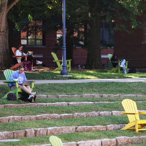 Students study in adirondack chairs near Memorial Hall Amphitheater