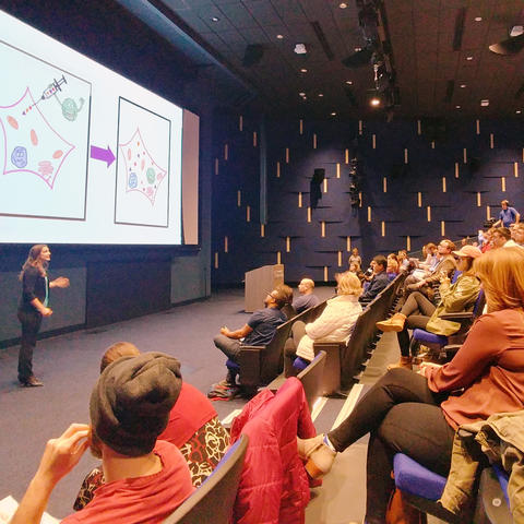 photo of student researcher presenting to audience in Worsham Cinema