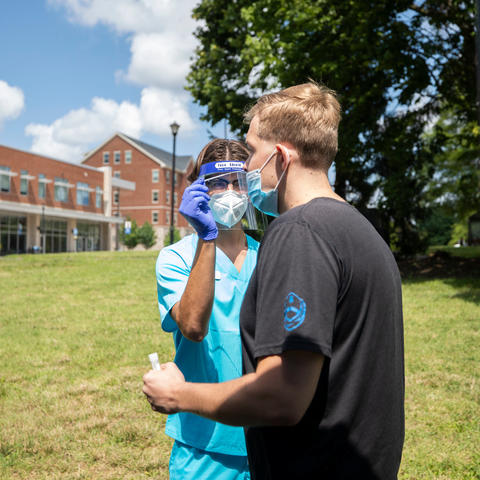 Wild Health employee administers a COVID-19 swab test to a UK student on Aug. 3 at the outdoor testing site across the street from The 90.