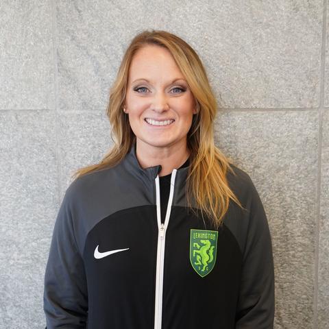 taylor spyker standing and smiling with lexington sporting club zip up jacket on