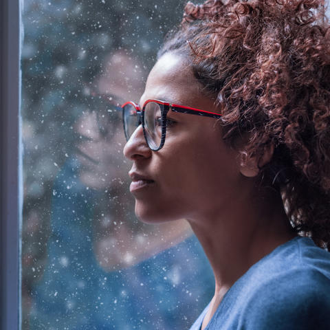 young woman looking out snowy window