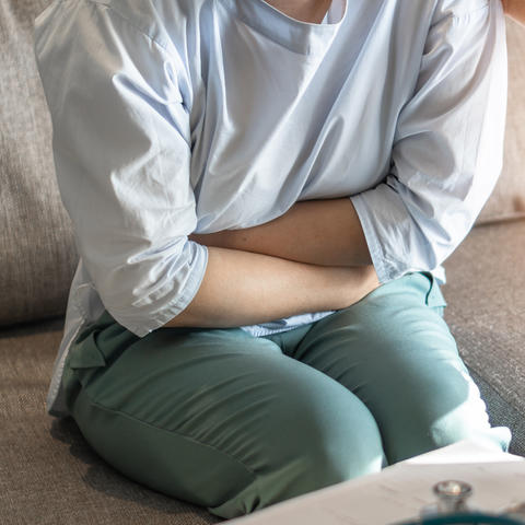 girl on couch clutching stomach