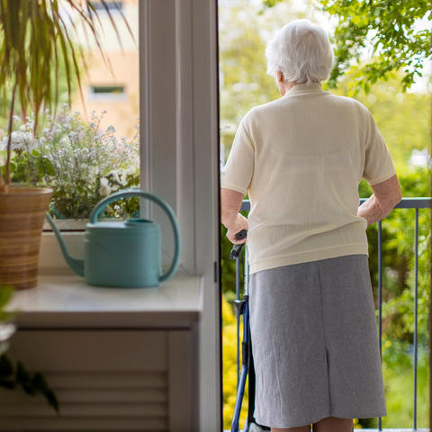 Woman with walker looks over balcony.