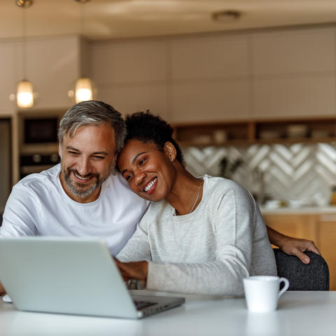 Couple smiling at laptop in kitchen