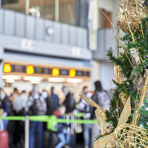 Flying in Christmas concept. Detail of big Christmas tree with golden ornaments with line of people in background