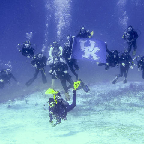Students holding a UK Flag while scuba diving