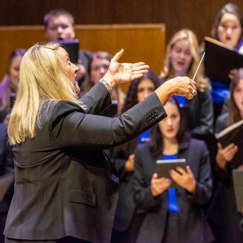 Woman conducting a choir on a stage