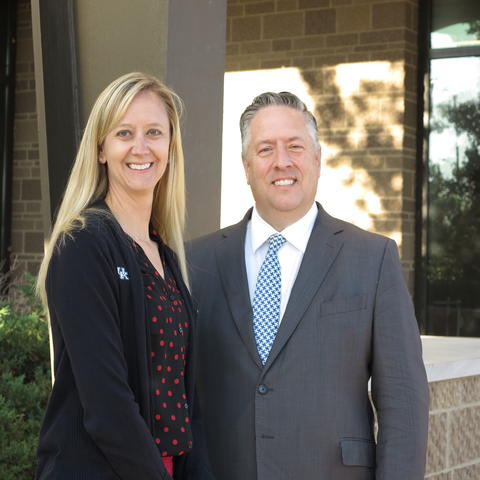 Photo of woman with blonde hair standing next to man with gray hair outside a building