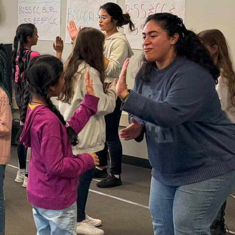 UK music education majors practice rhythm exercises with elementary school students by hand clapping.