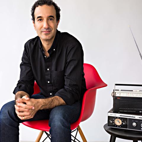 photo of Jad Abumrad seated in red chair next to radio