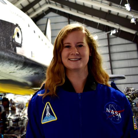 headshot photo of Esther Putman in NASA jumpsuit in front of shuttle