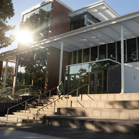 photo of front of the Rosenberg College of Law Building and a student walking up the steps