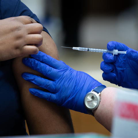 person in latex gloves administers covid 19 vaccine shot in arm to UK HealthCare employee.