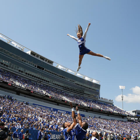 photo of a cheerleader being thrown in the air at a football game at Kroger Field