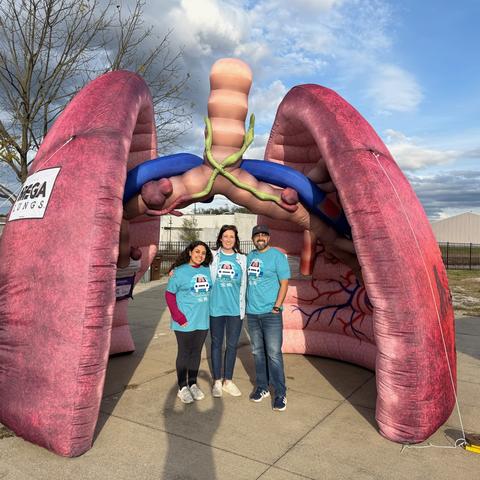 Three people standing in front of an inflatable lung. 