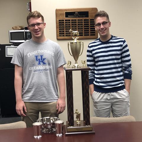 two guys standing with a trophy 