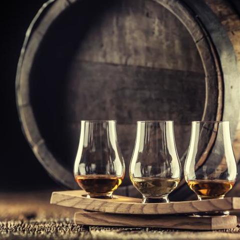 Glasses of whisky in front of barrel 