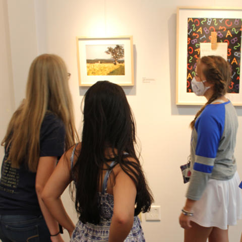 image of students looking at photographs at exhibit.