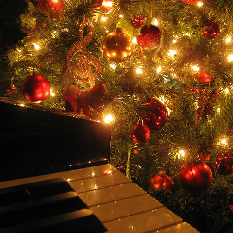 photo of Christmas tree with red ornaments and musical symbols next to piano