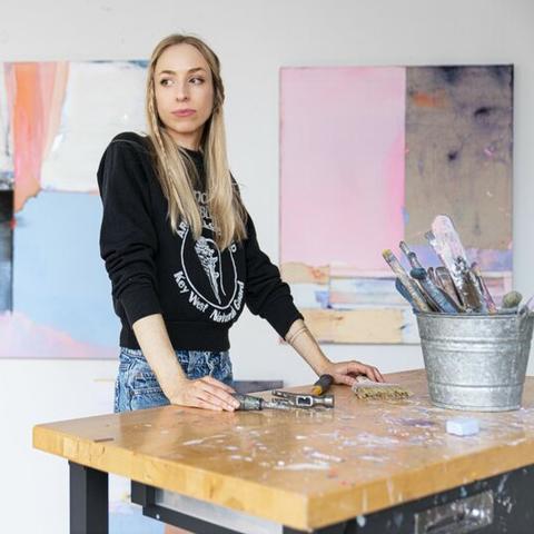 photo of Dana James in her studio with paintings behind her