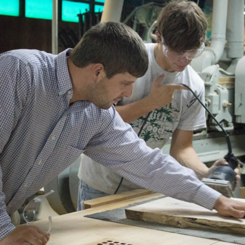 Chad Niman inspects Garrett Dunn’s work in a workshop.