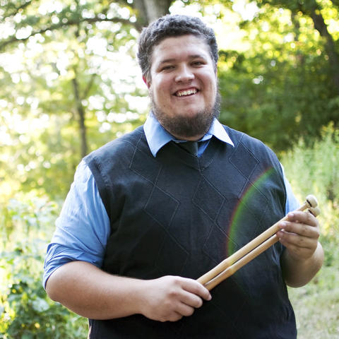 photo of Tyler Swick holding drumsticks outside
