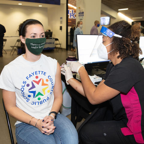 Teacher with Fayette County Public Schools T-shirt receives COVID-19 vaccine shot at Kroger Field vaccination clinic.