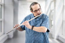 White man in light blue shirt playing flute