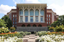 The William T. Young Library is pictured from the front, with landscaped flower beds and a walkway leading to the building entrance.