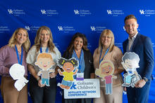 Five conference attendees pose with cartoon child cutouts and an Affiliate Network Conference sign in front of a UK Golisano Children’s Network backdrop.