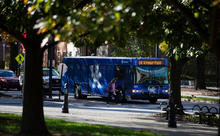 A student walking into a blue bus with the UK logo on the side. 
