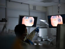 A clinician reviews procedure images on monitors in a hospital treatment room.