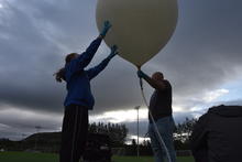 Two people holding a balloon.