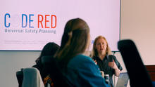 Person presents CODE RED Universal Safety Planning training to a group seated in a conference room.
