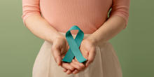 Person holding teal ribbon for ovarian cancer awareness
