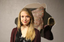 Person standing in front of an abstract wall sculpture.