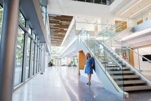A person stands beside the main staircase in the bright, modern interior of Scovell Hall.