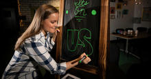 Photo of Lenzi Dodgen Writing “It’s on Us” on Chalkboard. 