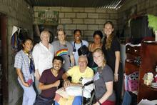 Group of volunteers and community members gathered inside a home for a photo.