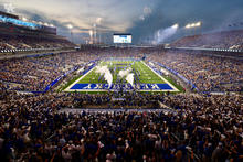 Photo of football stadium filled with large crowd and celebratory smoke being released in the end zone.