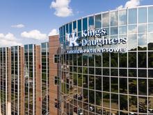 Exterior view of the UK King's Daughters Parkway Patient Tower, with the building name displayed on reflective glass windows under a blue sky with clouds.