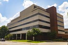 A multi-story building with brick and stone exterior under a partly cloudy sky.
