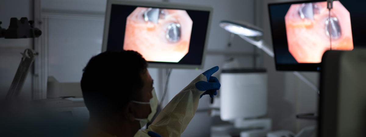 A clinician reviews procedure images on monitors in a hospital treatment room.