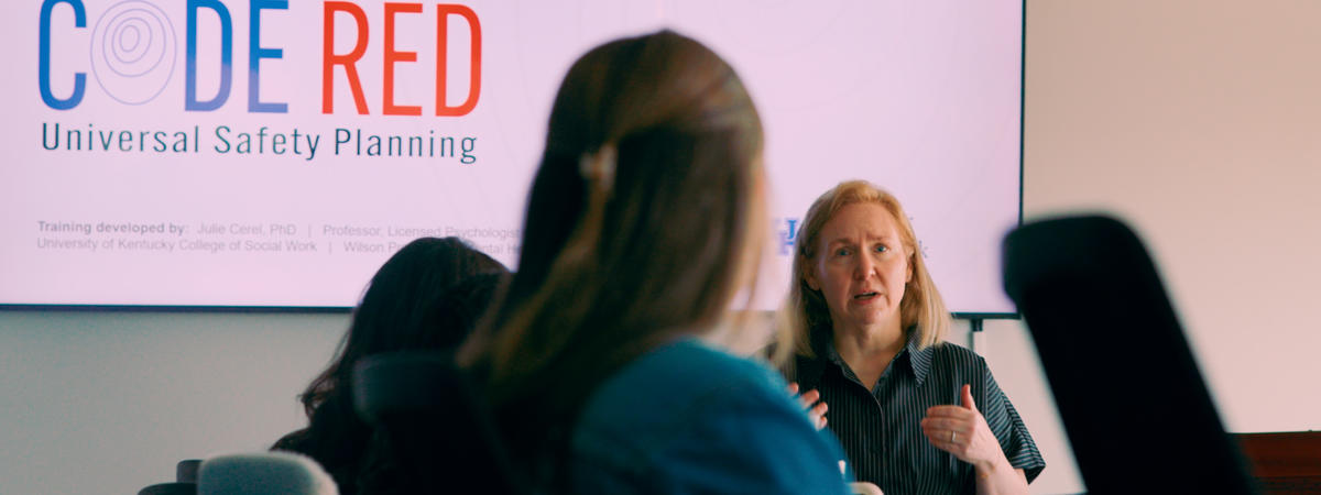 Person presents CODE RED Universal Safety Planning training to a group seated in a conference room.