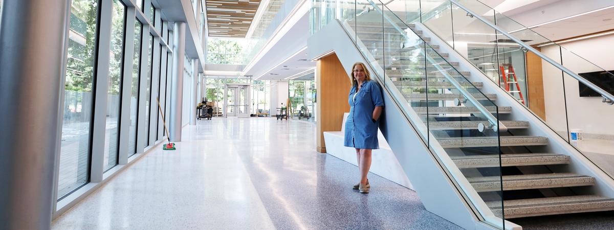 A person stands beside the main staircase in the bright, modern interior of Scovell Hall.