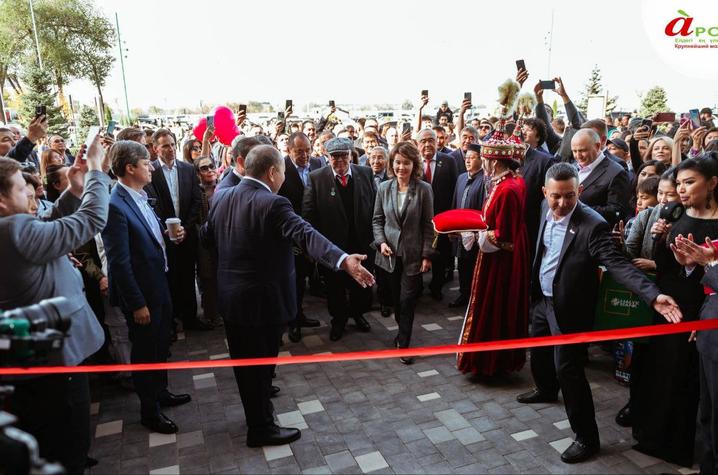A large crowd gathers outside a building during a ribbon-cutting ceremony.
